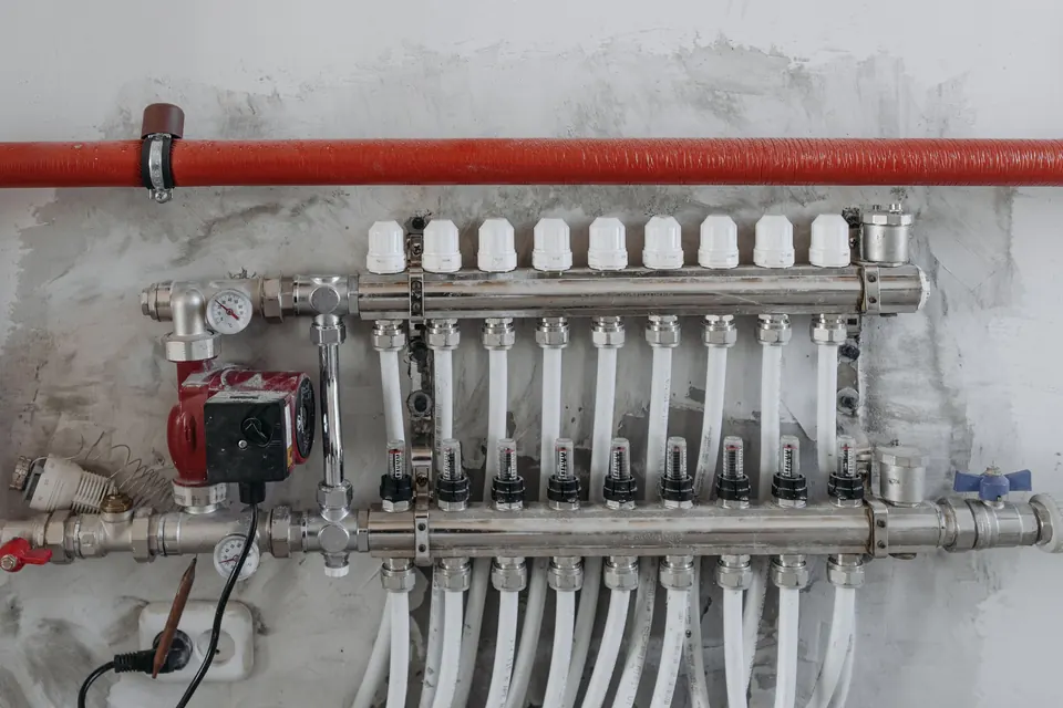 A plumbing manifold with valves and supply lines mounted on a wall