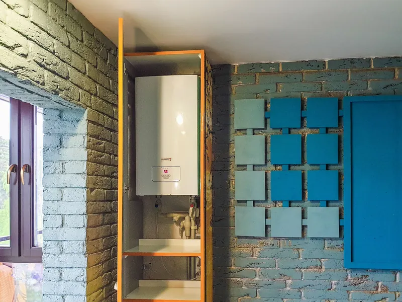 A wall mounted water heater installed in a cabinet beside a bathroom