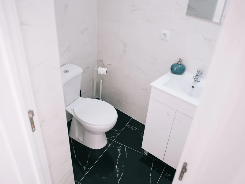 A bathroom with a white toilet, a vanity and a dark tile floor