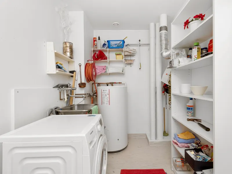 A home laundry room with a washing machine and a tank water heater